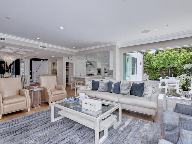 living room with hardwood / wood-style flooring, crown molding, and an inviting chandelier