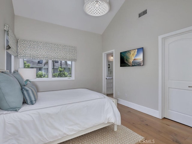 bedroom featuring ensuite bathroom, hardwood / wood-style floors, and high vaulted ceiling