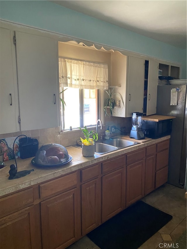 kitchen with refrigerator, backsplash, tile patterned floors, and sink