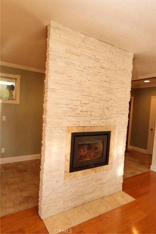 details featuring crown molding, a stone fireplace, and tile patterned floors