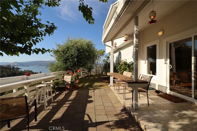 view of patio with a balcony and a water and mountain view