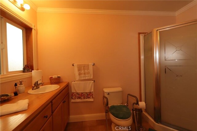 bathroom with ornamental molding, a shower with door, vanity, and toilet