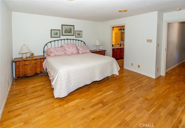 bedroom featuring connected bathroom and light hardwood / wood-style flooring