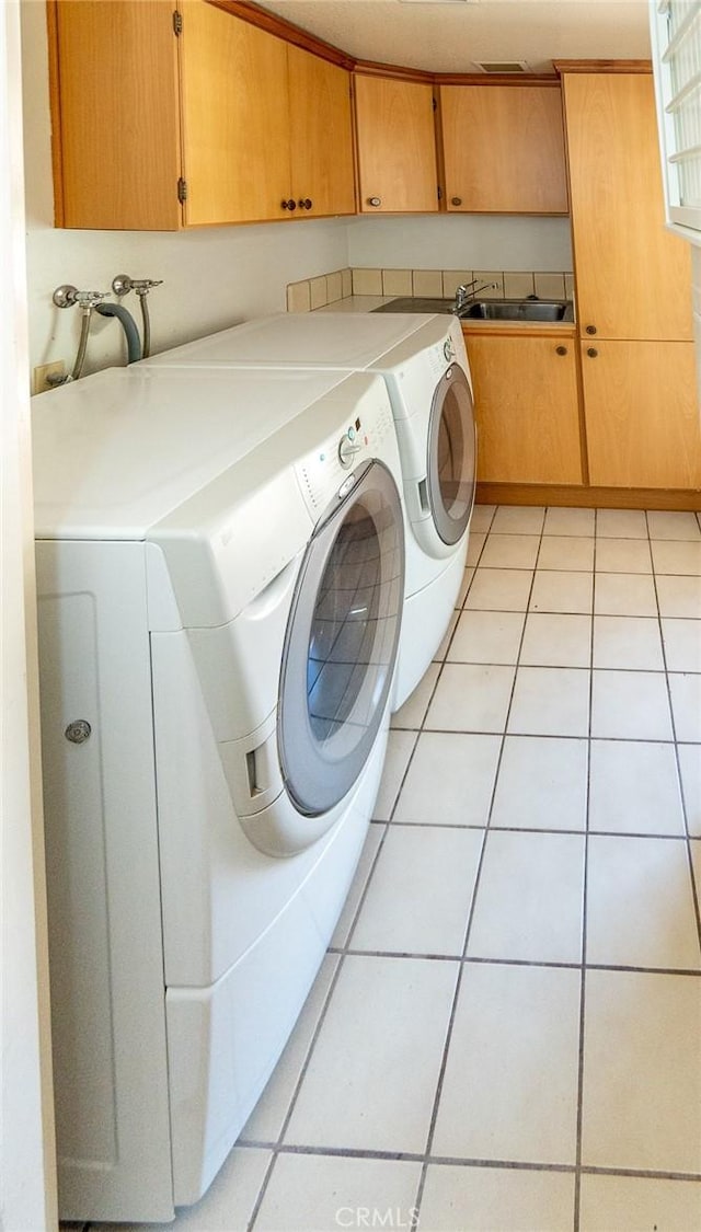 clothes washing area featuring washer and dryer, cabinets, light tile patterned floors, and sink