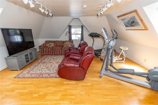 exercise room featuring wood-type flooring, track lighting, and vaulted ceiling