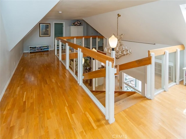 interior space featuring hardwood / wood-style flooring, a notable chandelier, and vaulted ceiling