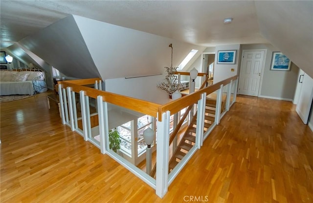 corridor featuring hardwood / wood-style flooring and vaulted ceiling