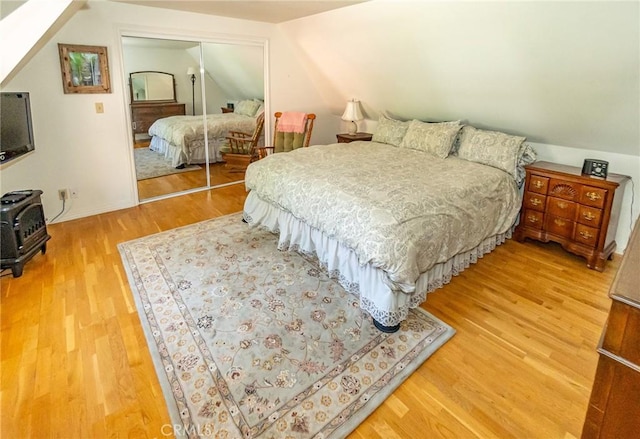 bedroom featuring hardwood / wood-style floors, vaulted ceiling, and a closet