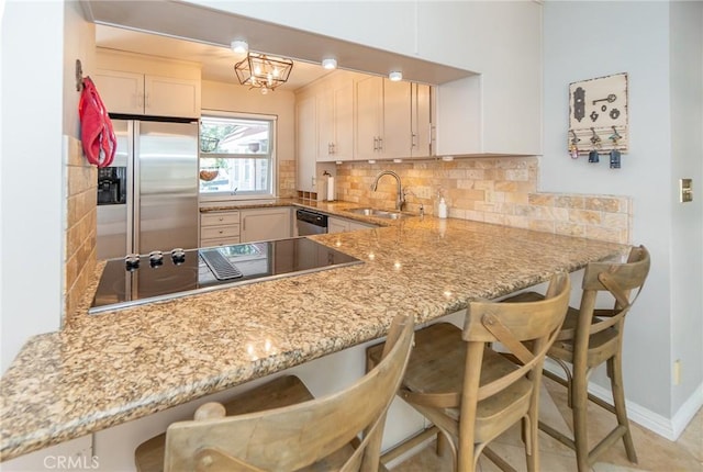 kitchen with kitchen peninsula, sink, a breakfast bar, and appliances with stainless steel finishes