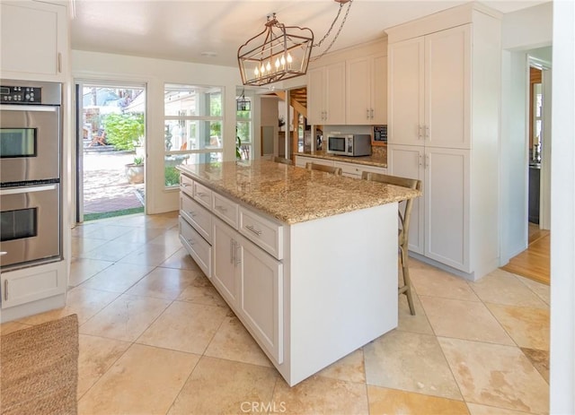 kitchen featuring white cabinets, a center island, pendant lighting, and stainless steel appliances