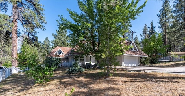 view of property hidden behind natural elements with a porch and a garage