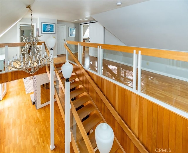 staircase with a barn door, wood-type flooring, and a notable chandelier