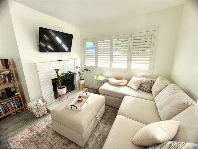 living area featuring a brick fireplace, baseboards, and wood finished floors