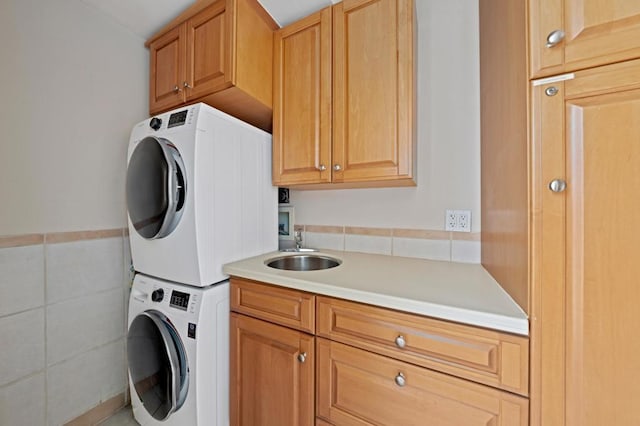 laundry room featuring stacked washer / dryer, sink, and cabinets