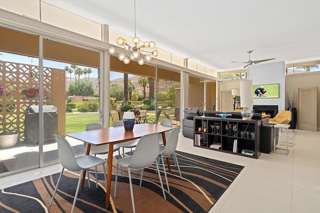 tiled dining room with ceiling fan with notable chandelier and plenty of natural light