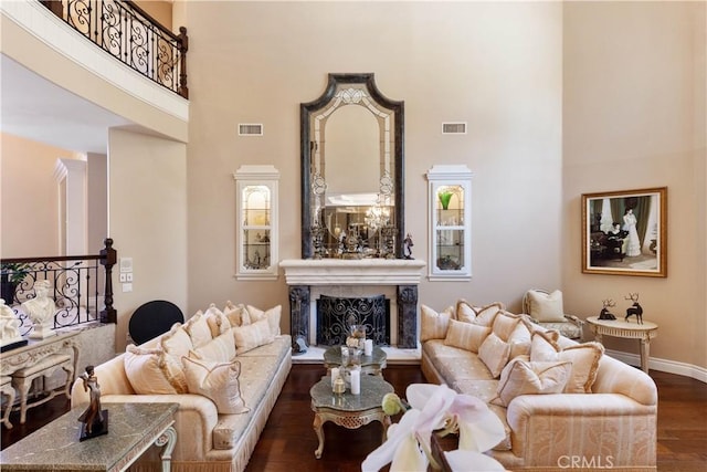 living room featuring a fireplace, a towering ceiling, and dark hardwood / wood-style flooring