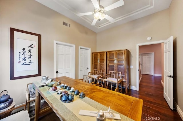 dining area featuring ceiling fan, dark hardwood / wood-style flooring, and a towering ceiling