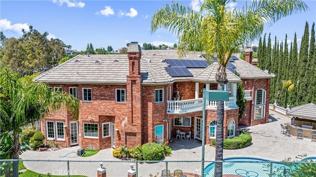 back of house featuring a fenced in pool, a patio area, and solar panels