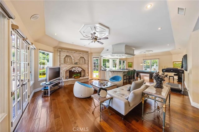 living room with hardwood / wood-style floors, a brick fireplace, and plenty of natural light