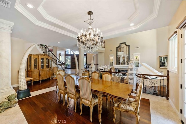 dining space with hardwood / wood-style floors, a raised ceiling, crown molding, and a notable chandelier