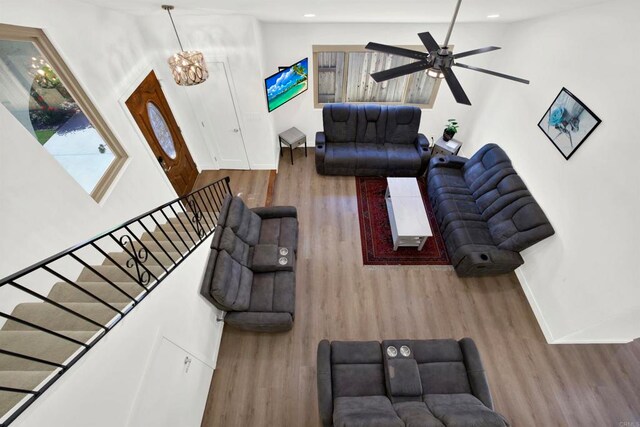 living room featuring hardwood / wood-style flooring, vaulted ceiling, and ceiling fan with notable chandelier