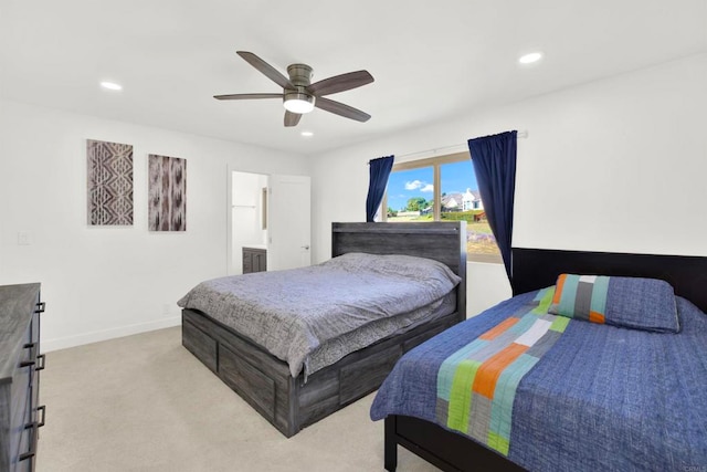 bedroom with connected bathroom, light carpet, and ceiling fan