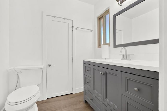 bathroom with hardwood / wood-style flooring, vanity, and toilet