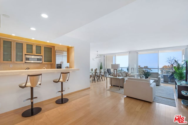 kitchen featuring a kitchen bar, stainless steel appliances, and light wood-type flooring