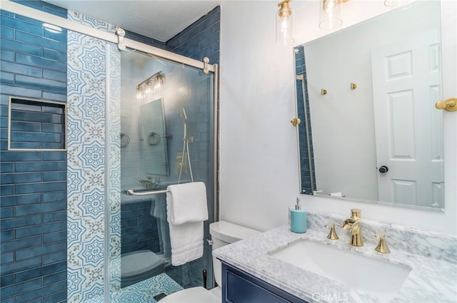 bathroom featuring a shower with shower door, toilet, and vanity