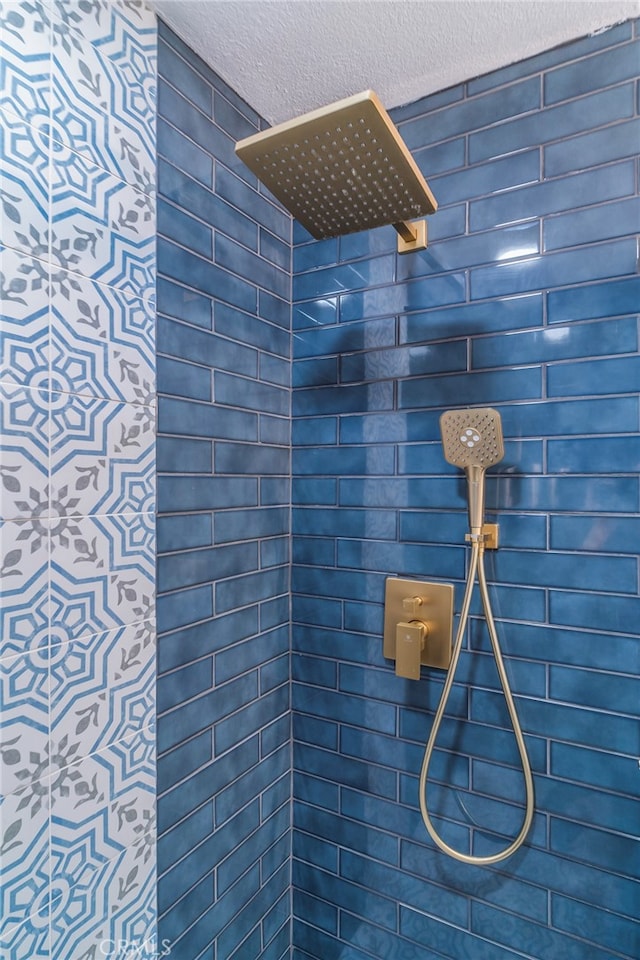 bathroom with a tile shower and a textured ceiling