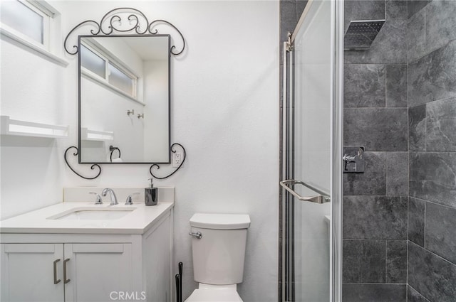 bathroom featuring a shower with shower door, vanity, and toilet