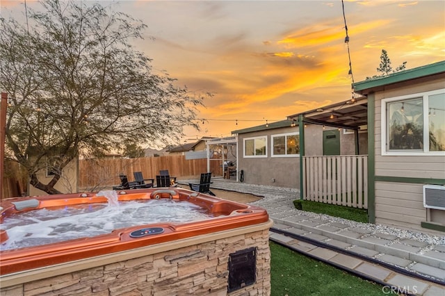 patio terrace at dusk featuring a hot tub