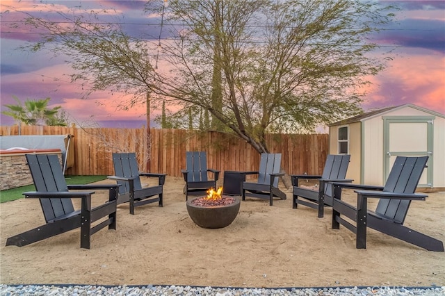 patio terrace at dusk featuring a shed and an outdoor fire pit