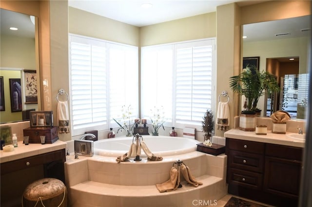 bathroom featuring vanity and tiled tub