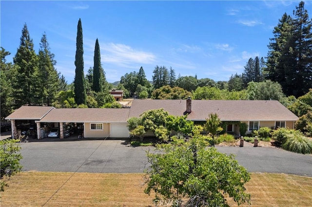 ranch-style house with driveway, a garage, a chimney, and an attached carport