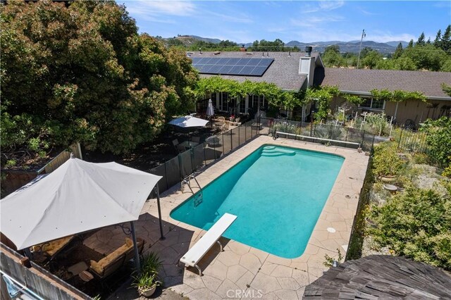 view of pool with a fenced in pool, a patio area, a mountain view, fence, and a diving board