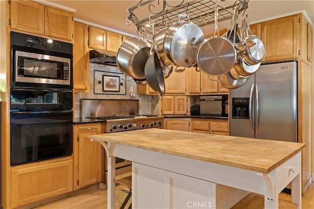 kitchen featuring a center island, stainless steel appliances, tasteful backsplash, butcher block counters, and light wood-style flooring