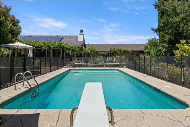 view of pool featuring a fenced in pool, fence, and a diving board