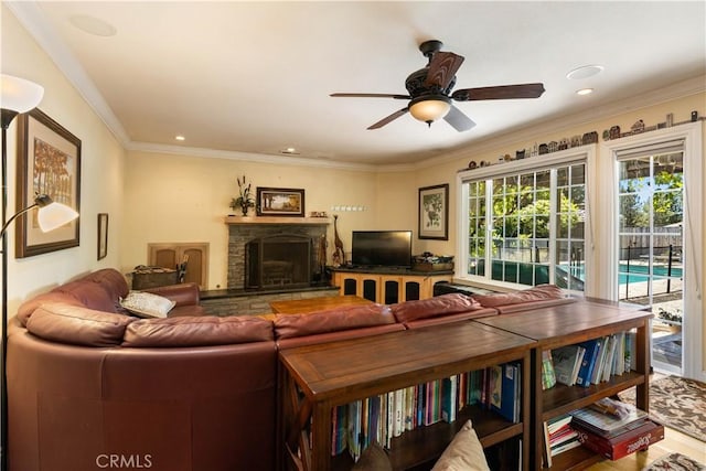 living area with ornamental molding, recessed lighting, a fireplace with raised hearth, and ceiling fan