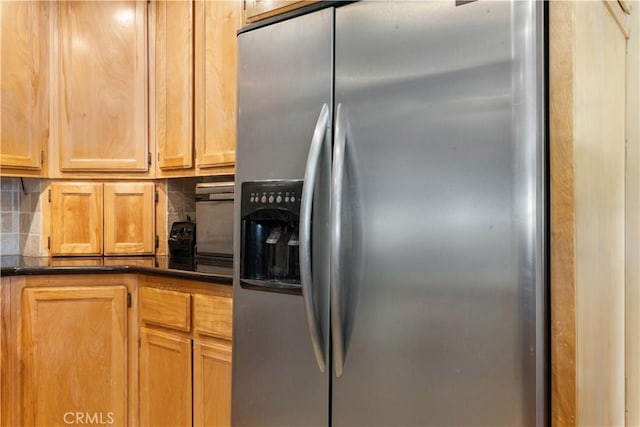 kitchen with dark countertops, stainless steel fridge, and backsplash