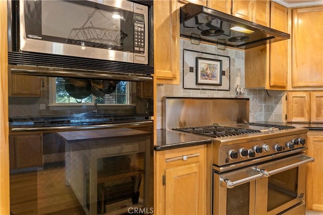 kitchen featuring stainless steel appliances, dark countertops, tasteful backsplash, wood finished floors, and under cabinet range hood