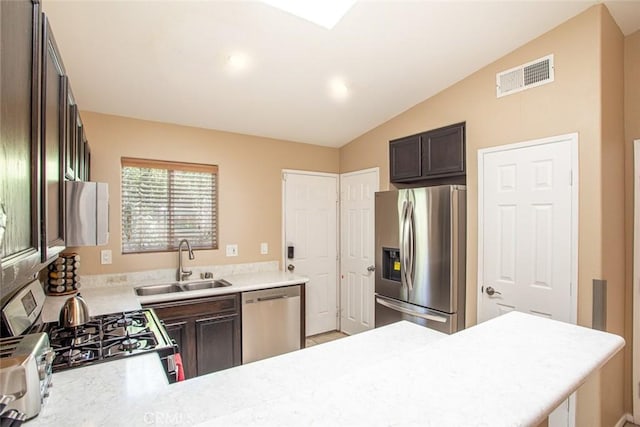 kitchen with dark brown cabinetry, sink, lofted ceiling, and appliances with stainless steel finishes