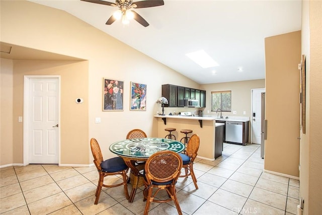 dining space featuring ceiling fan, light tile patterned floors, and vaulted ceiling