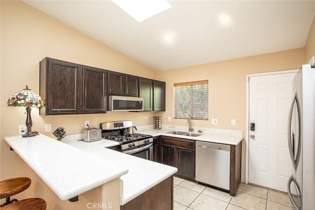 kitchen with kitchen peninsula, sink, stainless steel appliances, and lofted ceiling