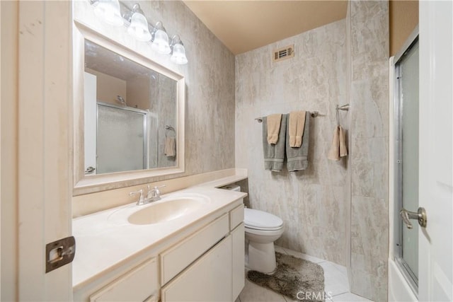 full bathroom featuring combined bath / shower with glass door, vanity, toilet, and tile walls