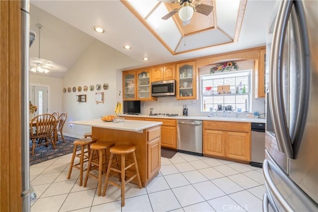 kitchen with a kitchen breakfast bar, a center island, stainless steel appliances, and ceiling fan