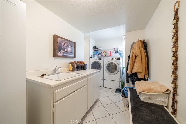 laundry area with cabinets, sink, washing machine and dryer, light tile patterned floors, and a textured ceiling