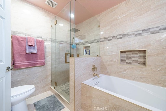 bathroom featuring toilet, tile walls, and shower with separate bathtub