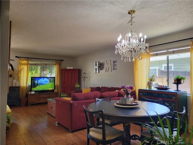 dining room with a notable chandelier, wood-type flooring, and a textured ceiling