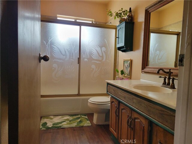 full bathroom with shower / bath combination with glass door, toilet, vanity, and hardwood / wood-style flooring